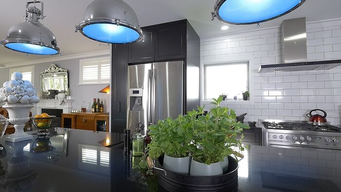 Modern kitchen with stainless steel appliances, subway tile backsplash, and blue pendant lights.